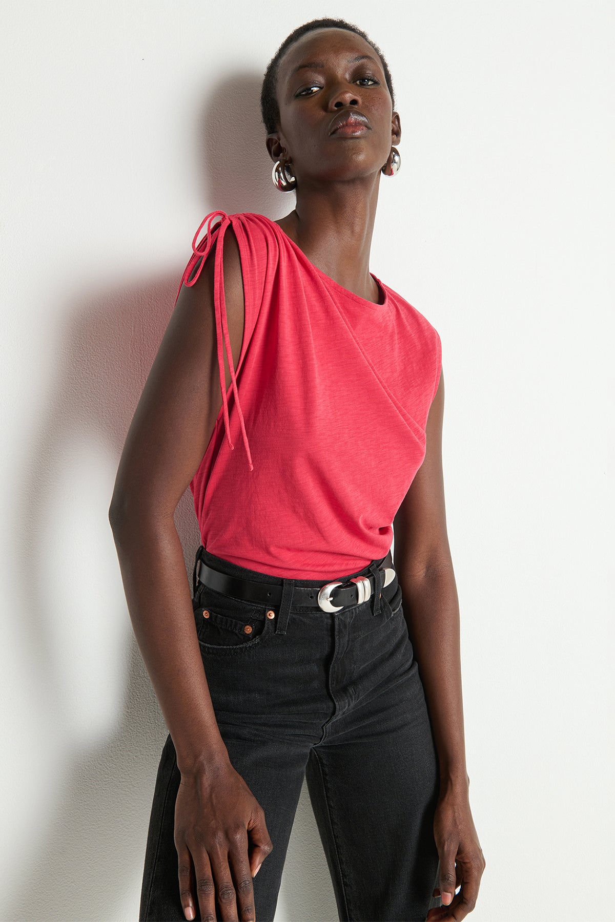 Woman wearing a pink top and black pants against a white background