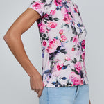 Person wearing a floral-patterned shirt with pink and blue flowers on a plain background