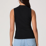 Woman wearing a black sleeveless knitted top and light blue jeans on a plain background