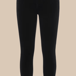 Black skinny jeans photographed flat against a solid beige background.
