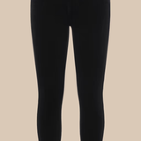 Black skinny jeans photographed flat against a solid beige background.