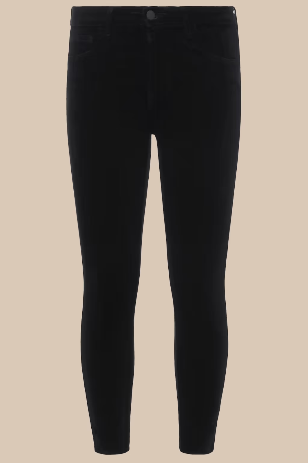 Black skinny jeans photographed flat against a solid beige background.
