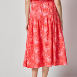 Woman wearing a red floral dress on a plain background