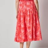 Woman wearing a red floral dress on a plain background