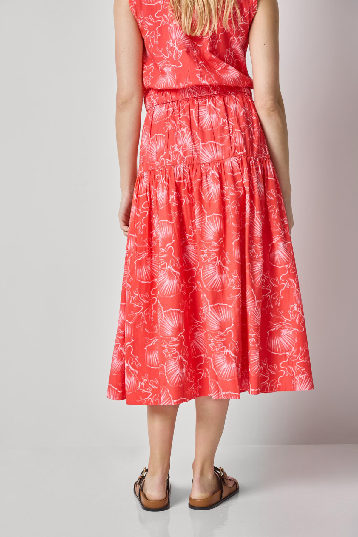 Woman wearing a red floral dress on a plain background