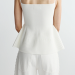 back of woman in ribbed white peplum tank on white background 