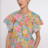 Woman wearing a colorful floral blouse against a white background