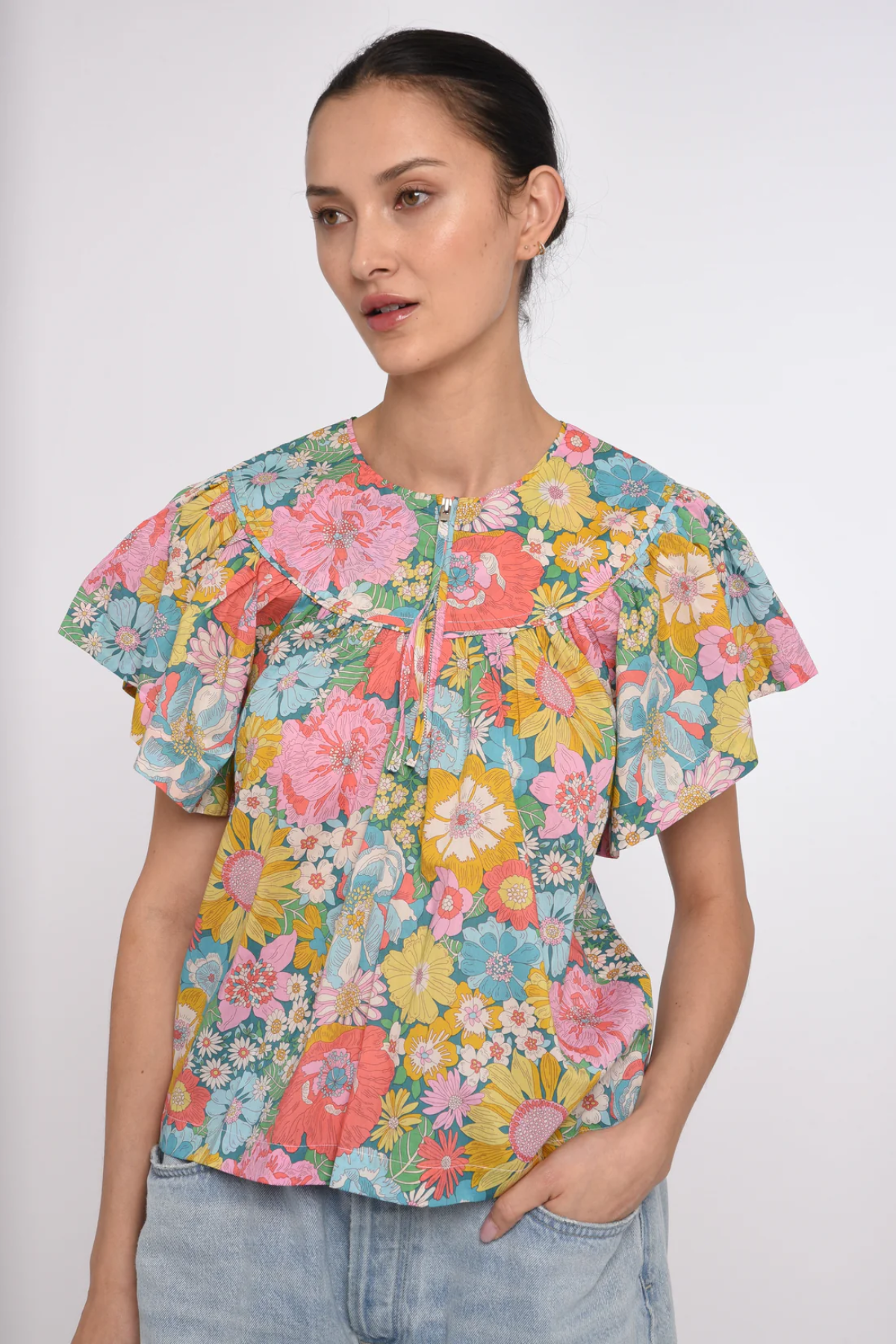 Woman wearing a colorful floral blouse against a white background