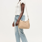 Woman holding a beige handbag against a white background