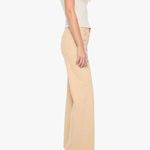 A woman shown from the side wearing a cream short-sleeve top, beige wide-leg trousers, and black high heels against a plain light gray studio background.