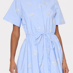 Woman wearing a blue and white striped dress with embroidered details on a white background
