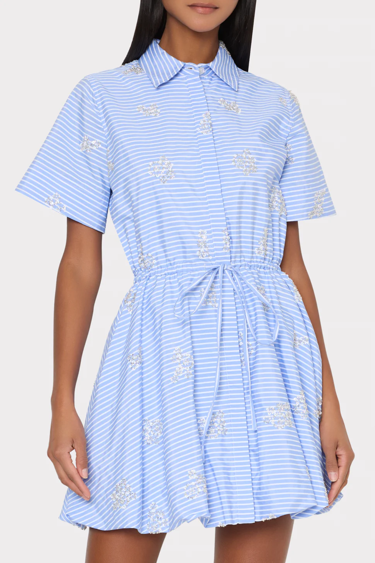 Woman wearing a blue and white striped dress with embroidered details on a white background