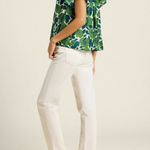 back of woman in green floral blouse on tan background 