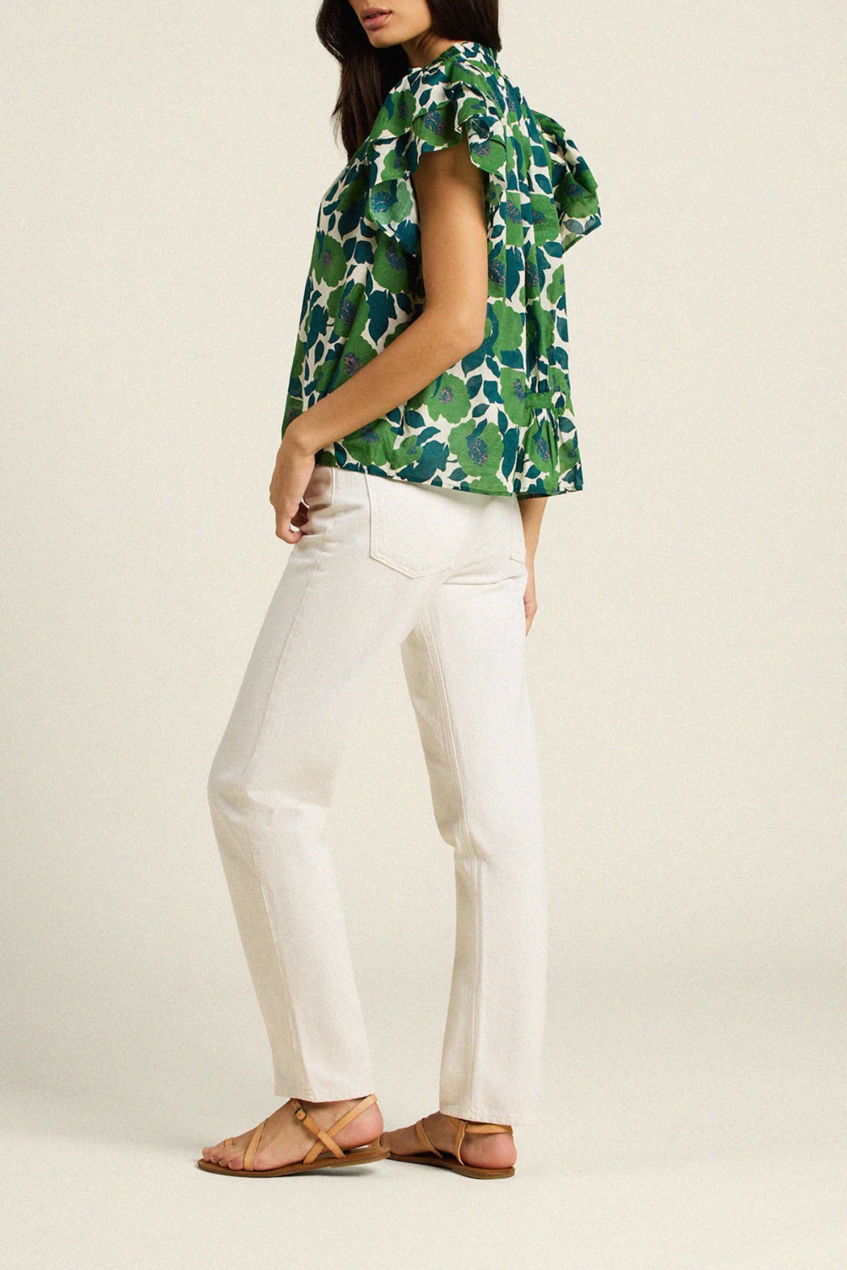 back of woman in green floral blouse on tan background 
