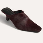 A single dark burgundy faux-hair mule heel shoe with a pointed toe, shown from a three-quarters angle on a light off-white background.