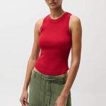 Person wearing a red sleeveless top and green pants on a white background