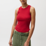 Person wearing a red sleeveless top and green pants on a white background