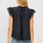 Person wearing a black sleeveless top with ruffled shoulders and blue jeans on a light gray background