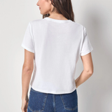 Woman wearing a white t-shirt and blue jeans against a plain background