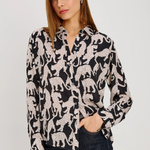 A woman modeling a black long-sleeve button-up shirt with a white leopard print pattern, paired with dark blue jeans, against a plain light gray background.