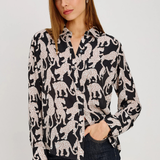 A woman modeling a black long-sleeve button-up shirt with a white leopard print pattern, paired with dark blue jeans, against a plain light gray background.