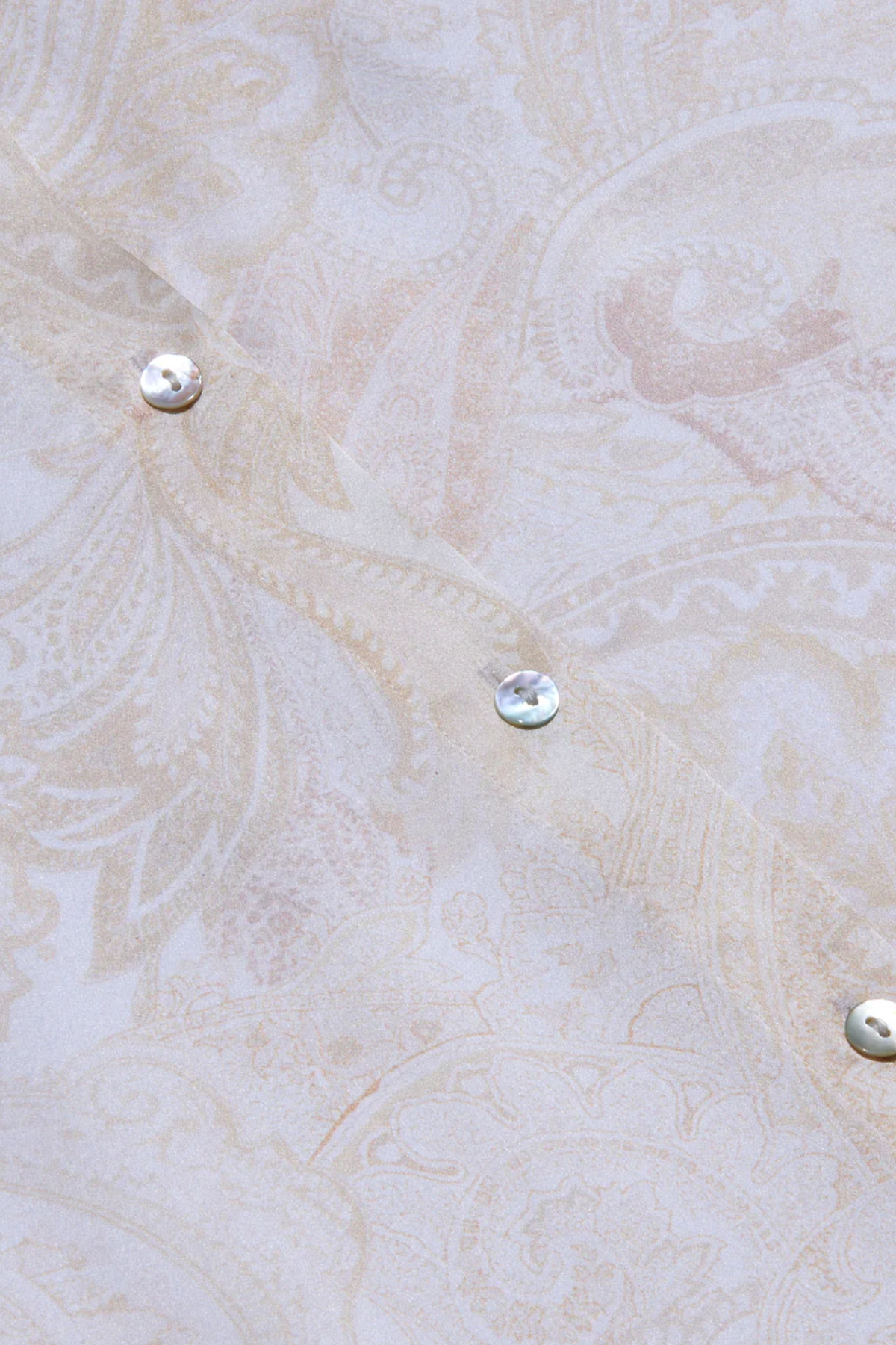 Close-up of a textured beige fabric with metallic buttons.