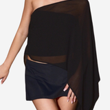 A woman modeling a black one-shoulder sheer wrap top with a matching black mini skirt against a plain light gray background.