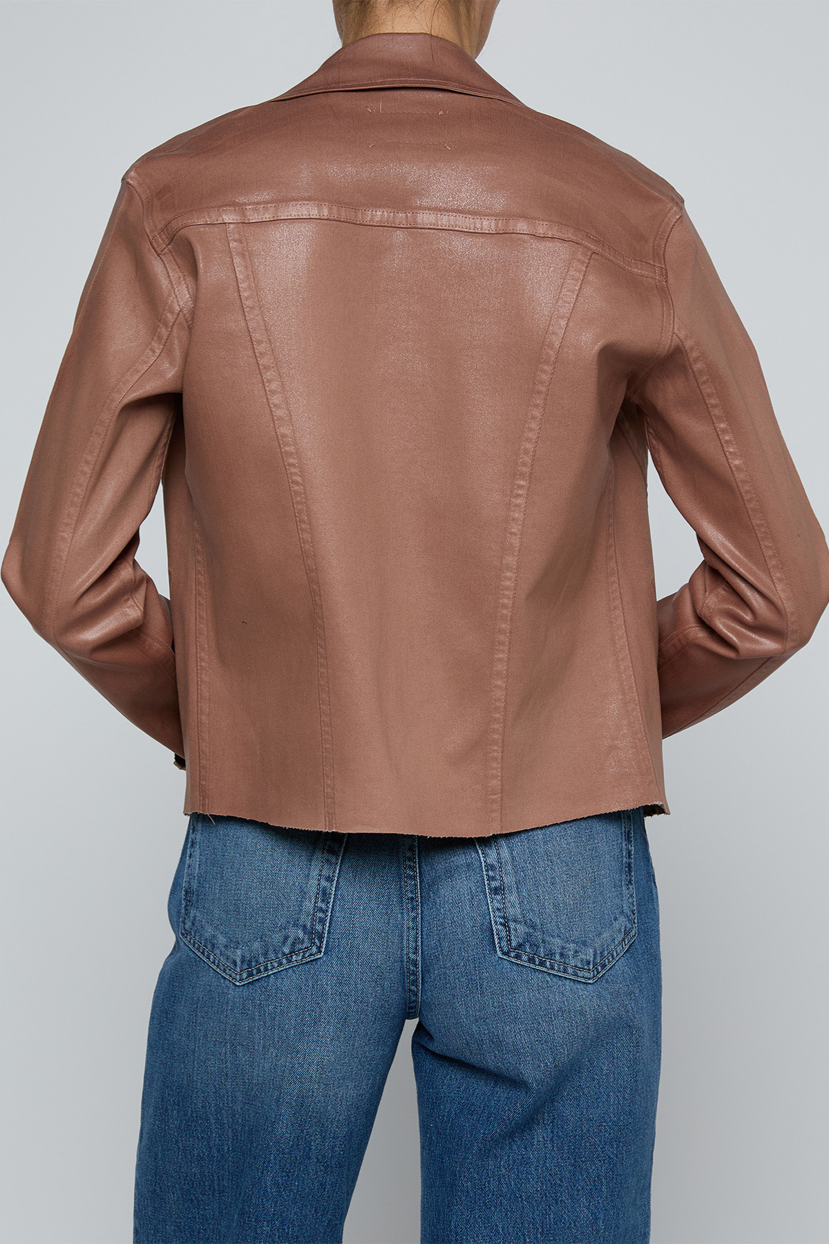Model wearing a light-wash slim-fit denim jacket with raw hem detailing and a button-front design.