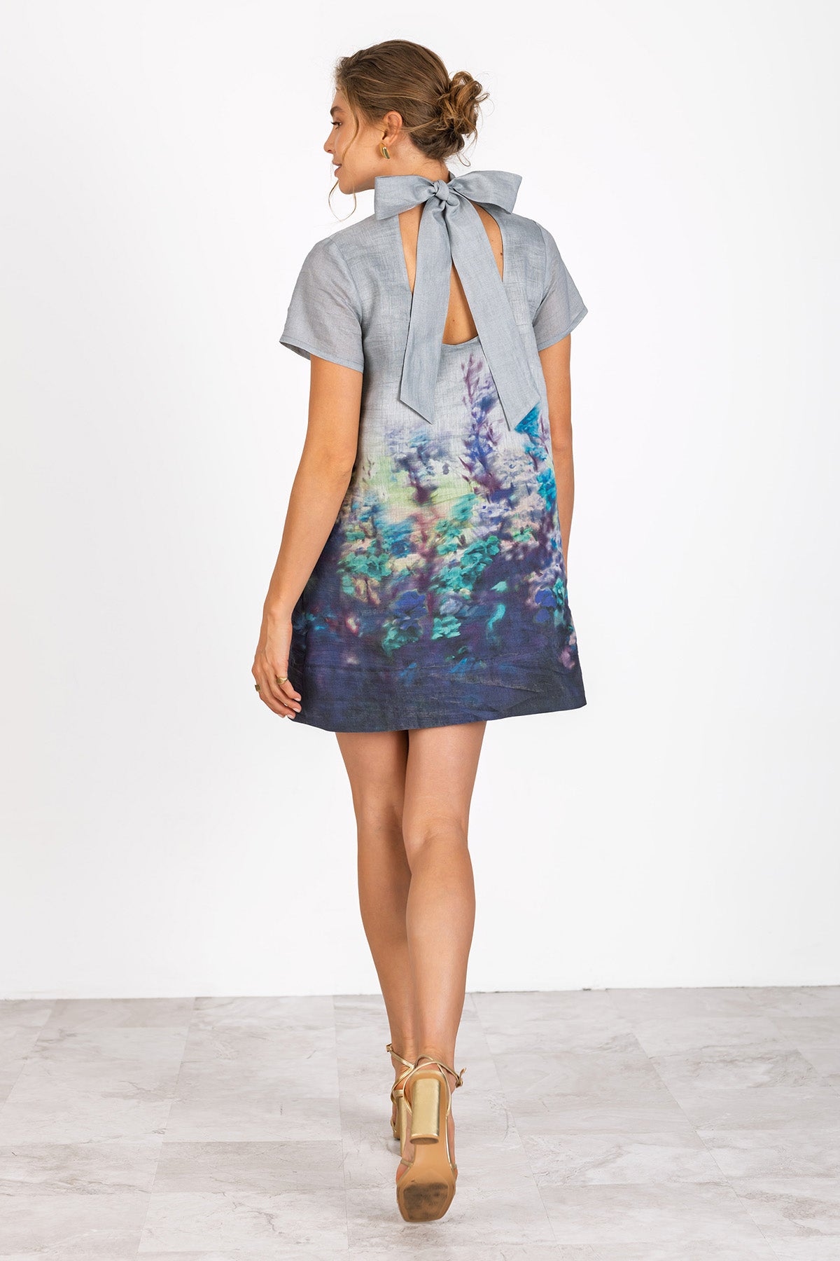 Woman wearing a gray dress with a colorful back design on a white background