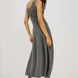 A woman modeling a sleeveless, scoop-neck gray knit midi dress, shown from a three-quarters back angle against a plain white studio background.