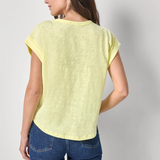 Woman wearing a light yellow top and blue jeans on a plain background