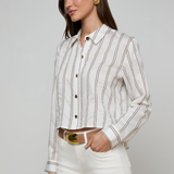 Woman wearing a white striped shirt and white pants on a gray background
