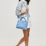Woman holding a blue textured handbag against a white background