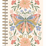 A spiral-bound notebook with a cream-colored cover featuring a colorful butterfly and floral design, bound with gold-toned metal coils on the left side.