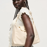 Woman wearing a beige top with ruffled sleeves and blue jeans on a white background