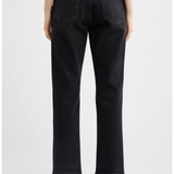 Rear view of a person wearing black cropped jeans with a straight-leg fit, paired with black pointed-toe heels against a light gray studio background.