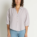Woman wearing a striped shirt and jeans against a plain background