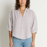 Woman wearing a striped shirt and jeans against a plain background