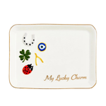 A white ceramic lucky charm tray with a gold rim, featuring traditional good luck symbols including a green four-leaf clover, a red ladybug, a white horseshoe, an evil eye, and a gold/yellow yankee, with the text 'My Lucky Charm' in gold script.