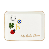 A white ceramic lucky charm tray with a gold rim, featuring traditional good luck symbols including a green four-leaf clover, a red ladybug, a white horseshoe, an evil eye, and a gold/yellow yankee, with the text 'My Lucky Charm' in gold script.