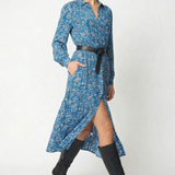 A woman models a blue floral long-sleeve midi dress with a black belt and black knee-high heeled boots against a plain light gray studio background.