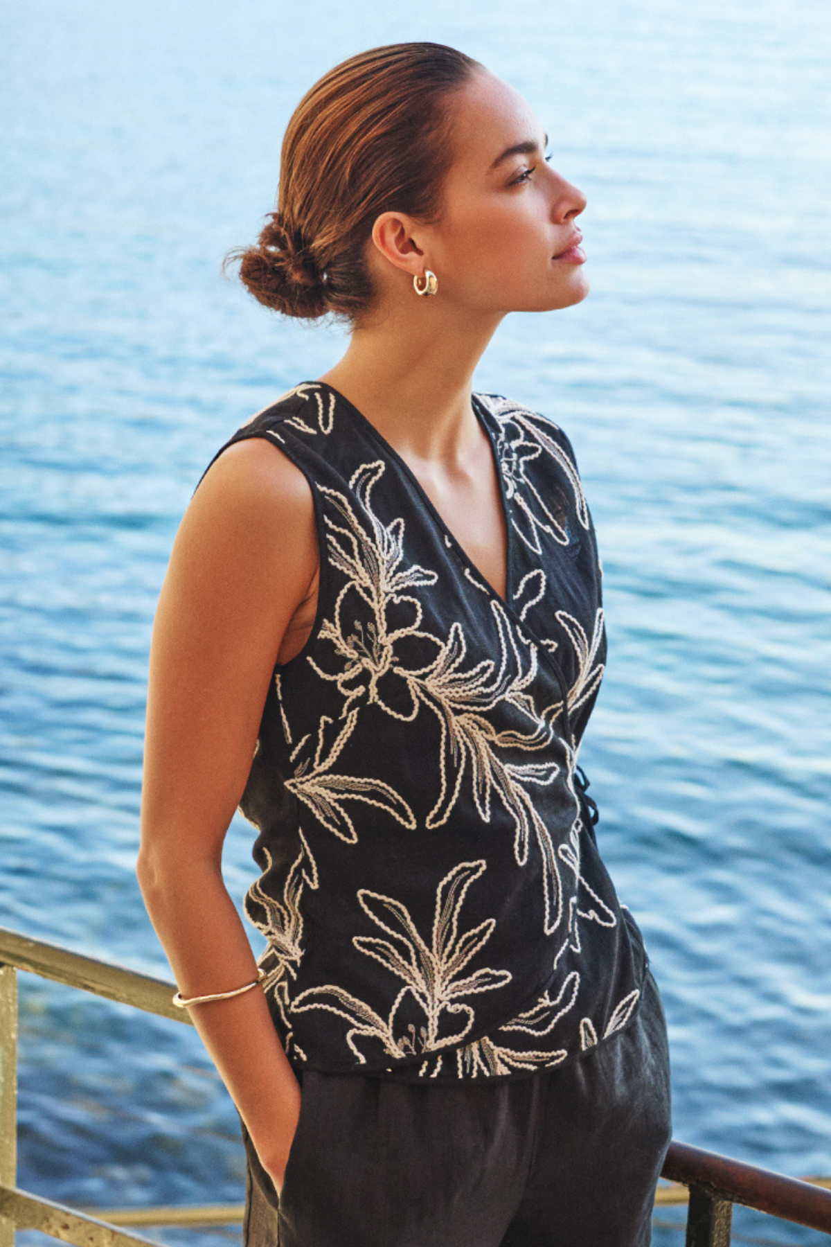 Woman wearing a black floral top by a body of water