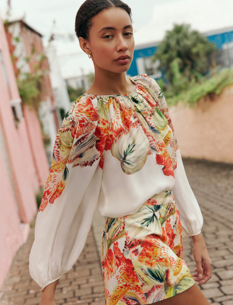 Woman wearing a colorful floral outfit with a blurred outdoor background
