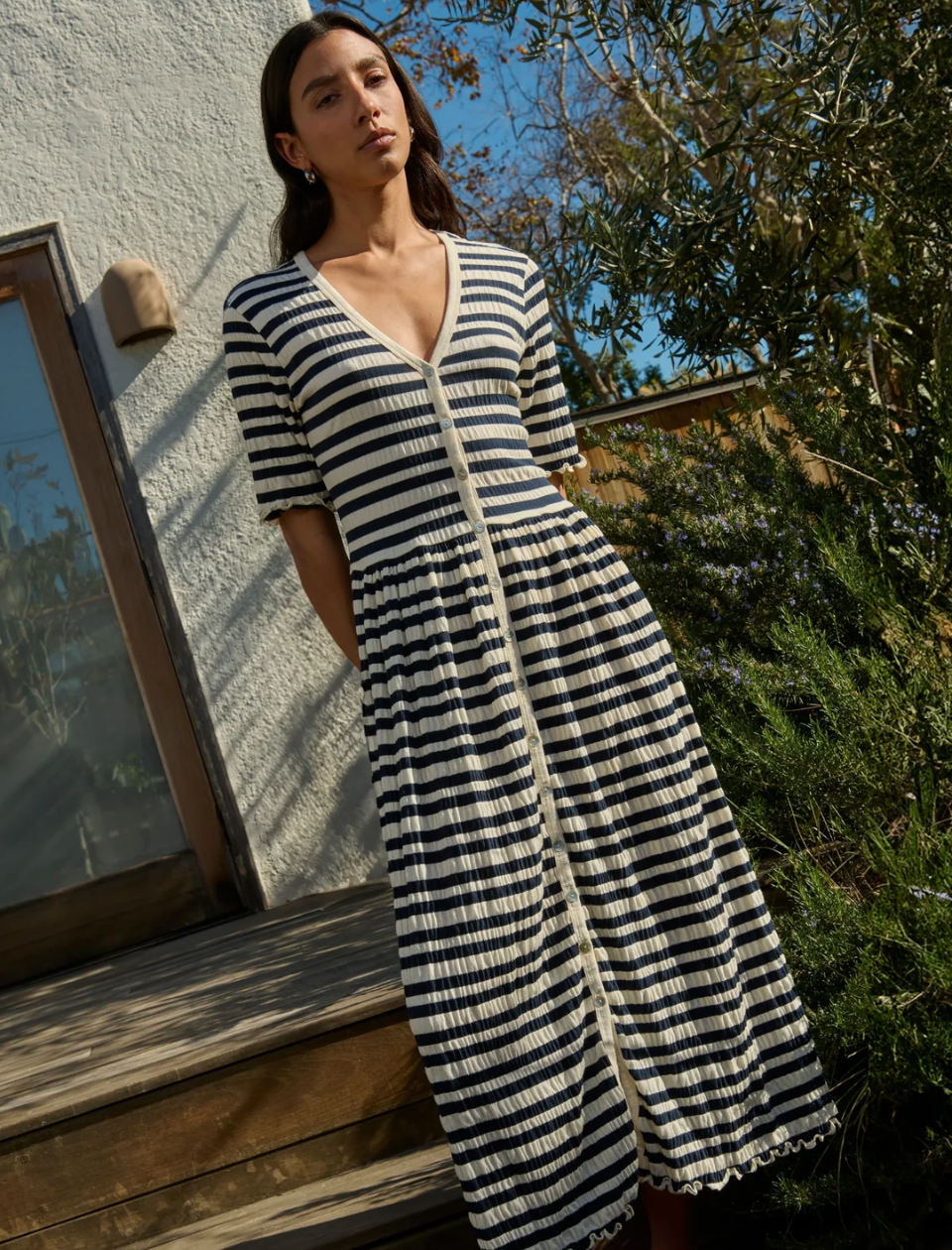 Woman wearing a black and white striped dress standing outdoors.