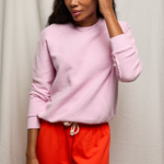 Woman wearing a pink sweater and red pants against a white background