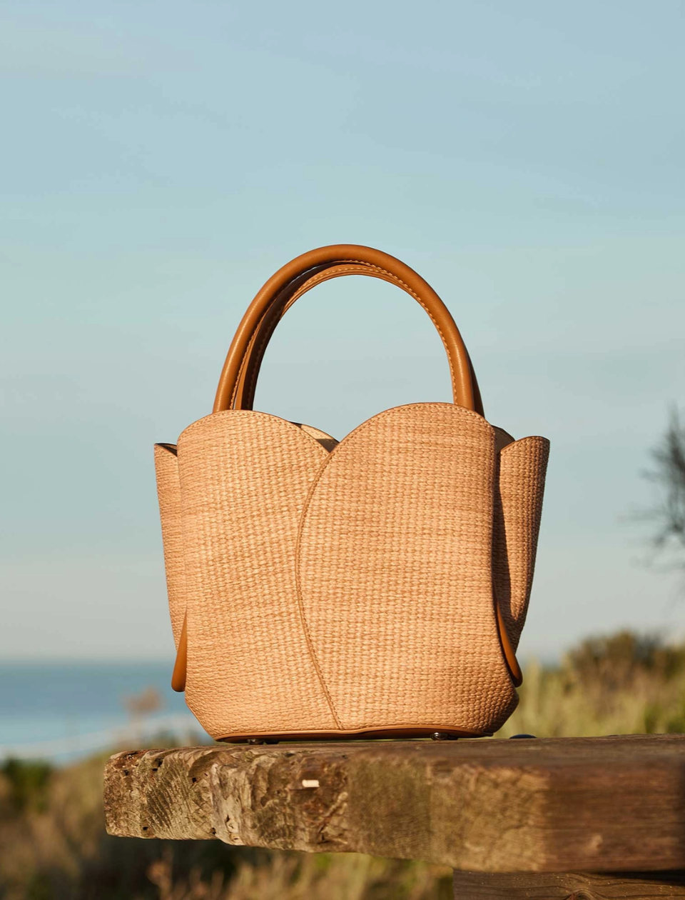 Woven handbag on a wooden surface with a blurred natural background