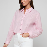 Woman wearing a pink ribbed blouse and white shorts on a gray background