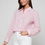 Woman wearing a pink ribbed blouse and white shorts on a gray background