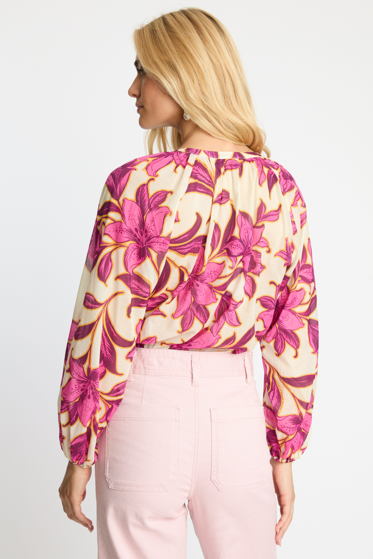 Woman wearing a floral blouse with pink and yellow flowers on a white background