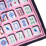 A close-up of a pink silk scarf featuring a traditional Chinese mahjong tile pattern with black borders and the INK+ALLOY brand name printed in the bottom right corner.